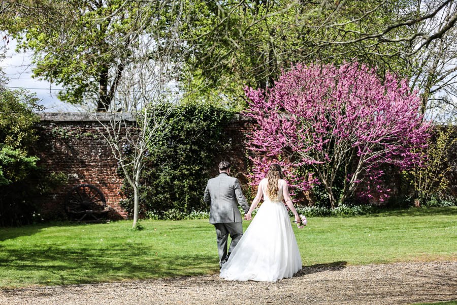Bride and groom walking through garden at Dorset outdoor wedding venue during ceremony