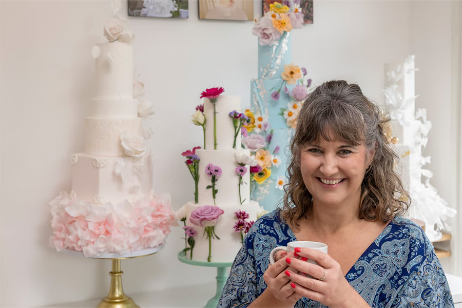 Angela from AT Cake Artistry wedding cake designer standing beside colourful bespoke wedding cakes
