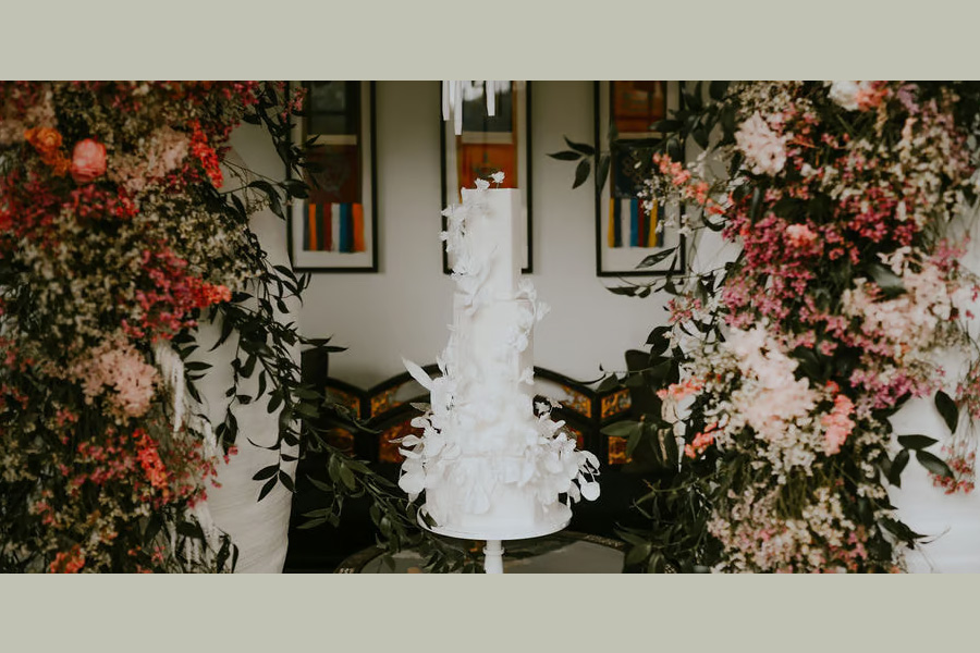 Luxury white wedding cake surrounded by large floral installations at Dorset wedding venue