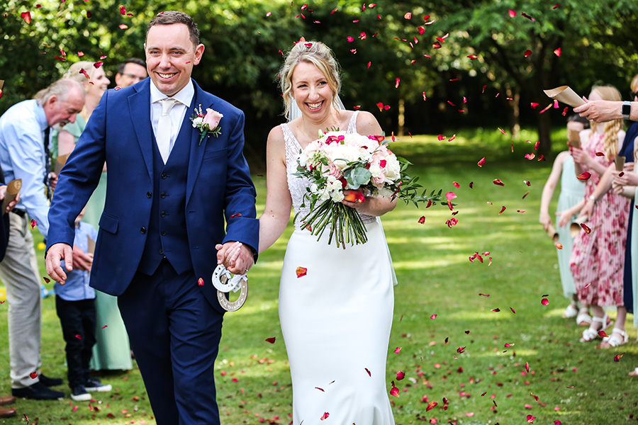 Bride with natural bridal makeup by Beauty By Harriet Emma walking down aisle after outdoor wedding ceremony