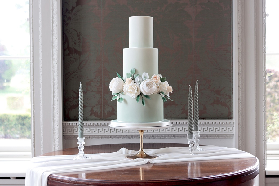 Tall modern wedding cake with white sugar flowers and sage green tier