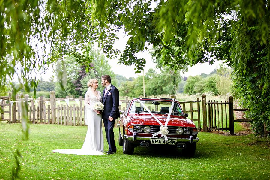 Bride and groom beside classic wedding car Dorset