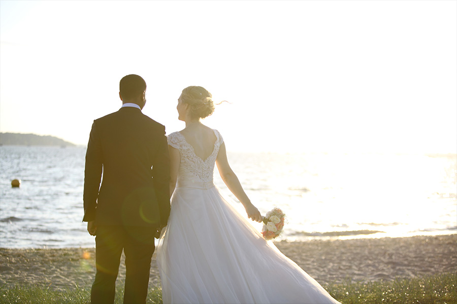 Bride and groom walking along the beach at a coastal wedding venue in Dorset in daylight