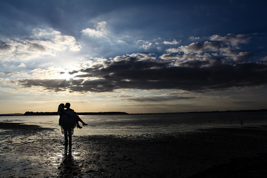 Couple at a coastal wedding venue in Dorset walking along the beach at sunset
