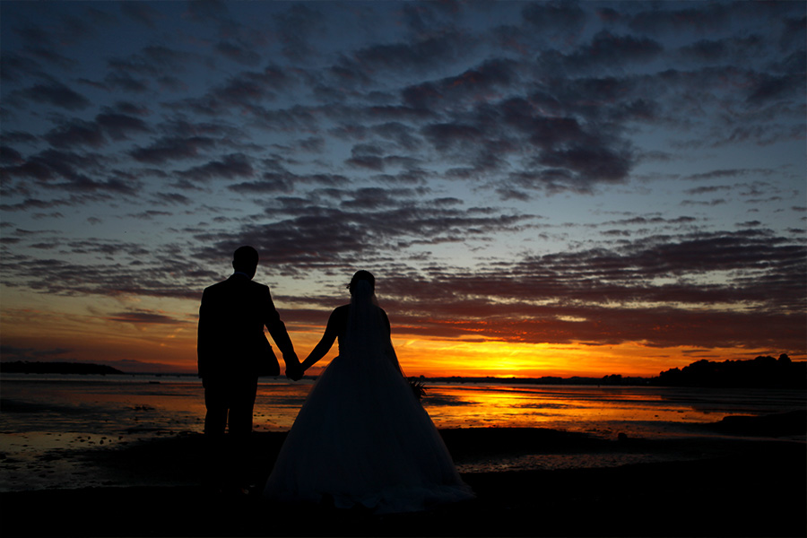 Couple walking along the beach at sunset at a coastal wedding venue in Dorset