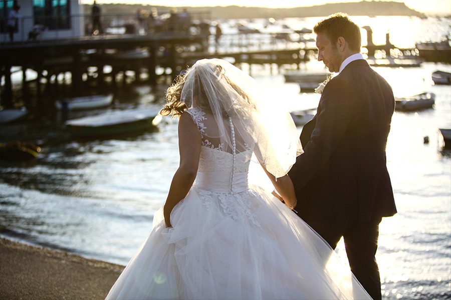 Bride and groom walking along a Dorset beach at sunset near a coastal wedding venue