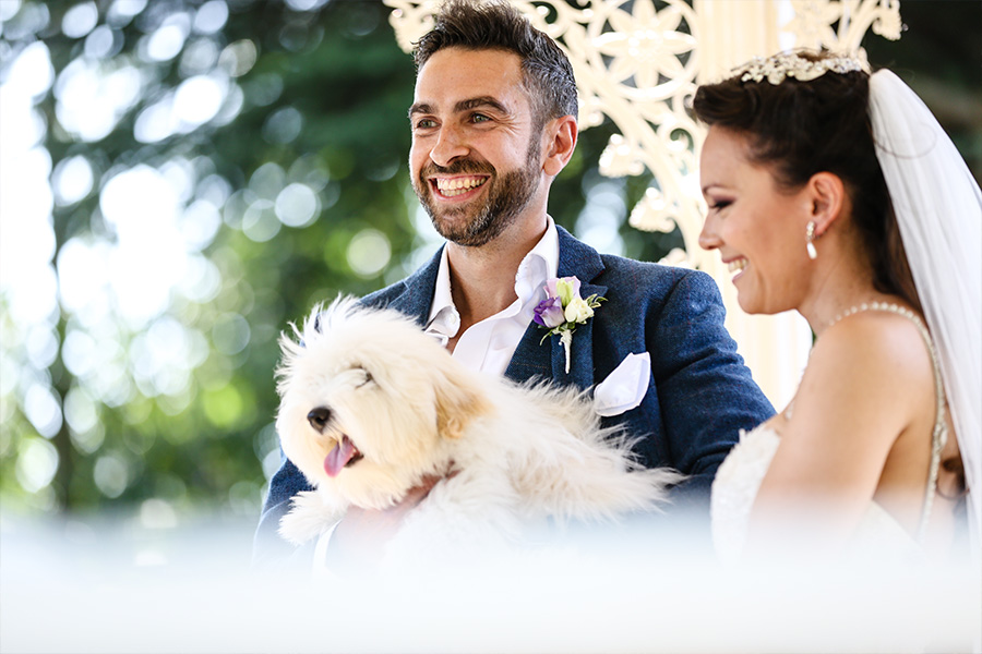 Bride and groom with dog during outdoor wedding ceremony in Dorset