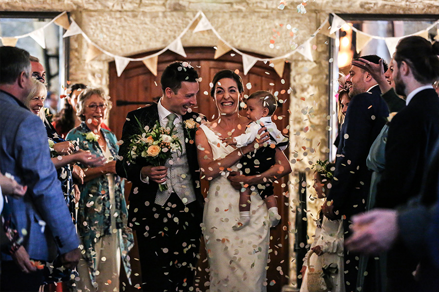 Couple walking through confetti at a Dorset wedding venue during a real wedding celebration