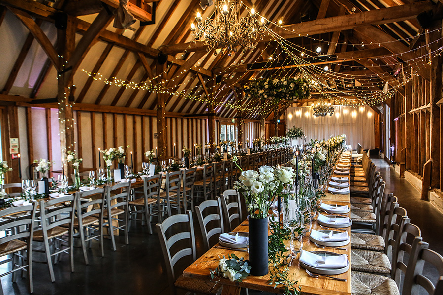 hampshire-barn-wedding-venue-rustic-reception-interior Rustic barn wedding venue in Hampshire set for a wedding reception with long tables and fairy lights
