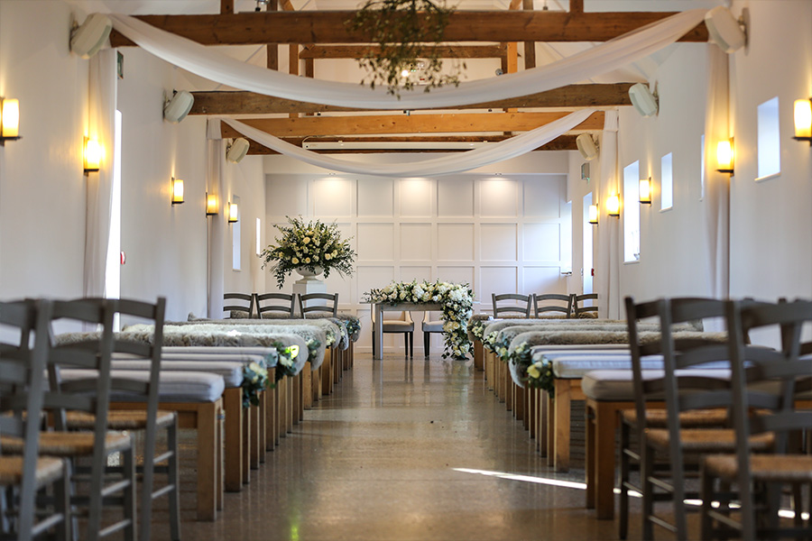 hampshire-luxury-wedding-venue-ceremony-space-elegant-interior Elegant ceremony space inside a luxury wedding venue in Hampshire with floral aisle and soft draping