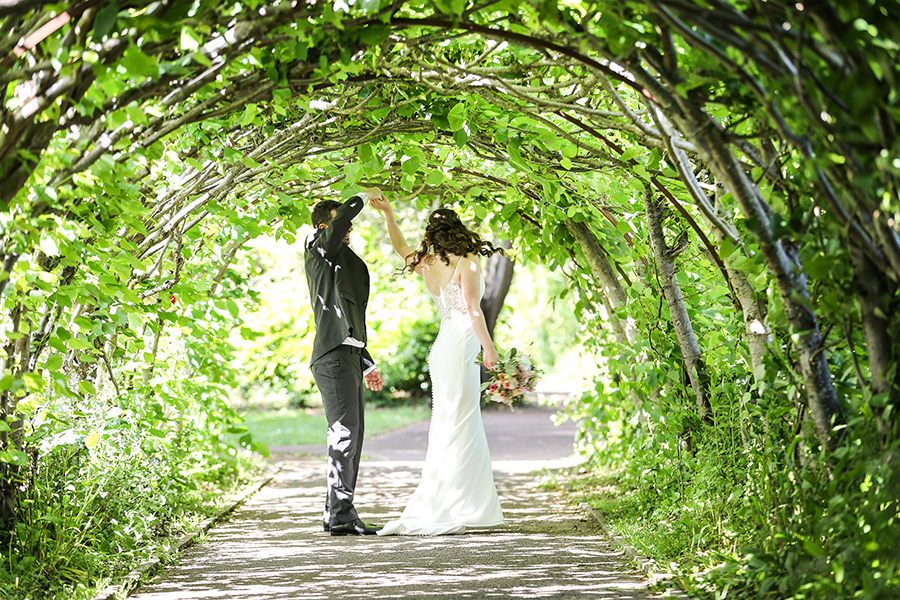 Bride and groom under a leafy garden archway at an outdoor wedding venue in Hampshire