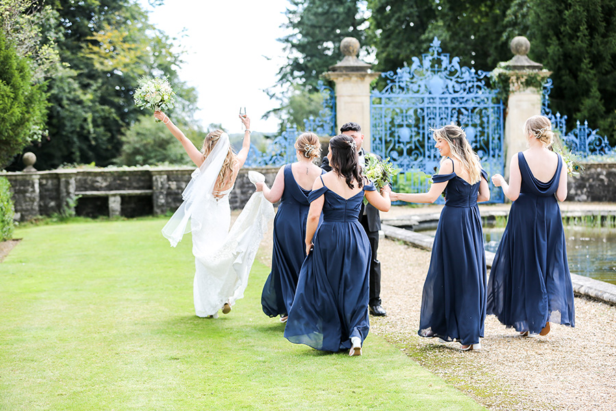 Hampshire wedding photographers capturing a bride and bridesmaids celebrating in the gardens at Rhinefield House.