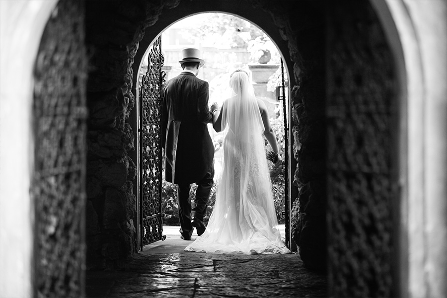 Bride and groom walking through a stone archway at a luxury wedding venue in Dorset