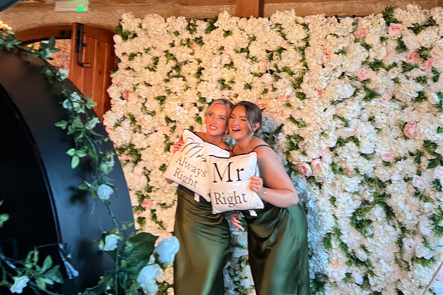 Two friends laughing and lifting each other in a wedding photo booth in Dorset