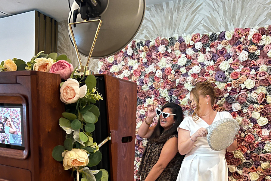 Guests enjoying a vintage style Pink Giraffe photo booth with floral backdrop at a Dorset wedding reception