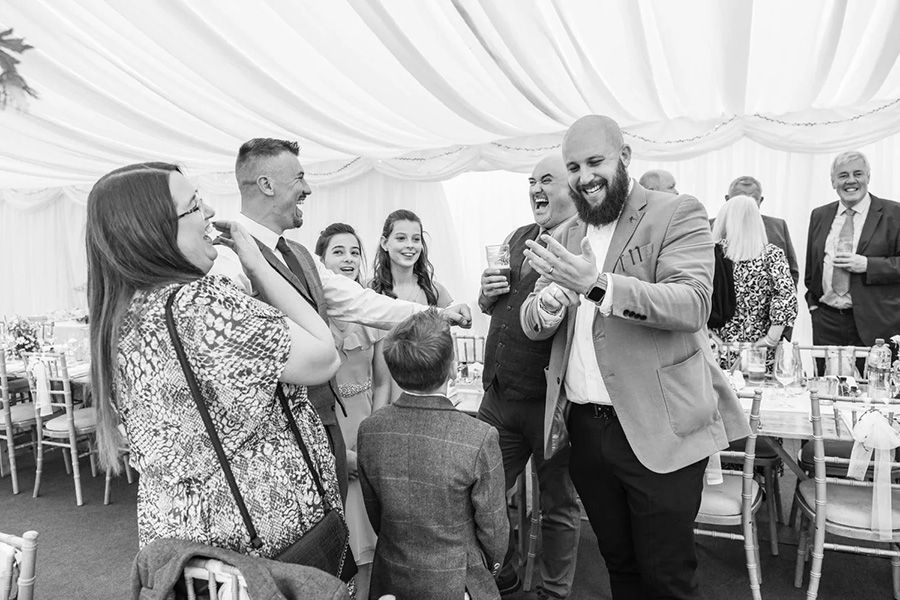 Close up wedding magician performing interactive entertainment for guests inside marquee reception
