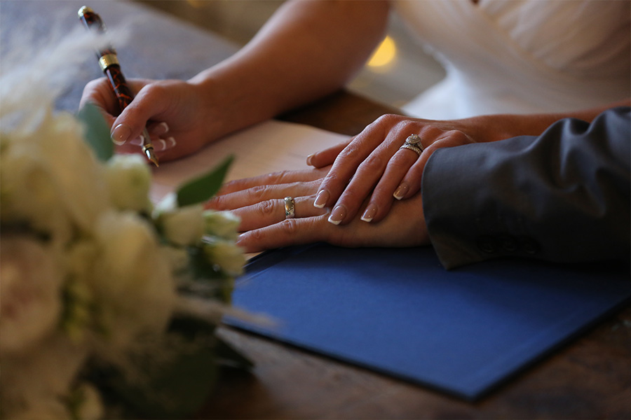 couple signing marriage register with rings visible during legal wedding ceremony England