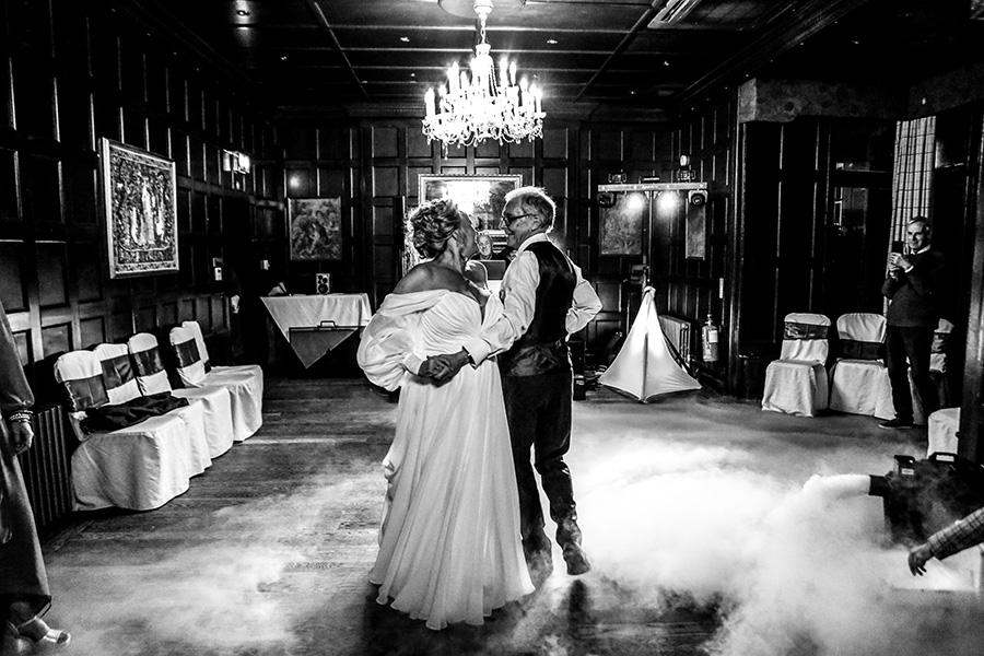 Bride and groom sharing romantic first dance surrounded by low fog on dance floor