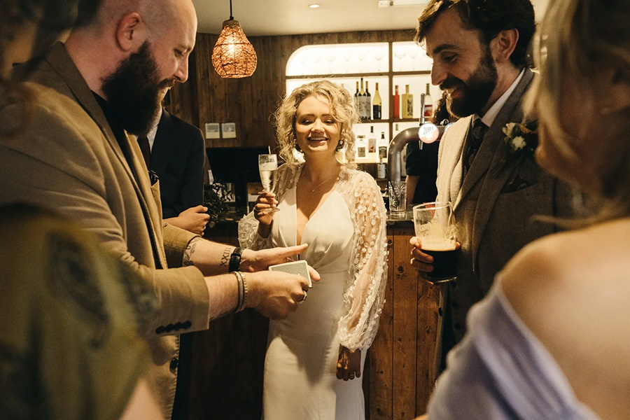 Wedding magician performing close up magic for bride and guests during drinks reception