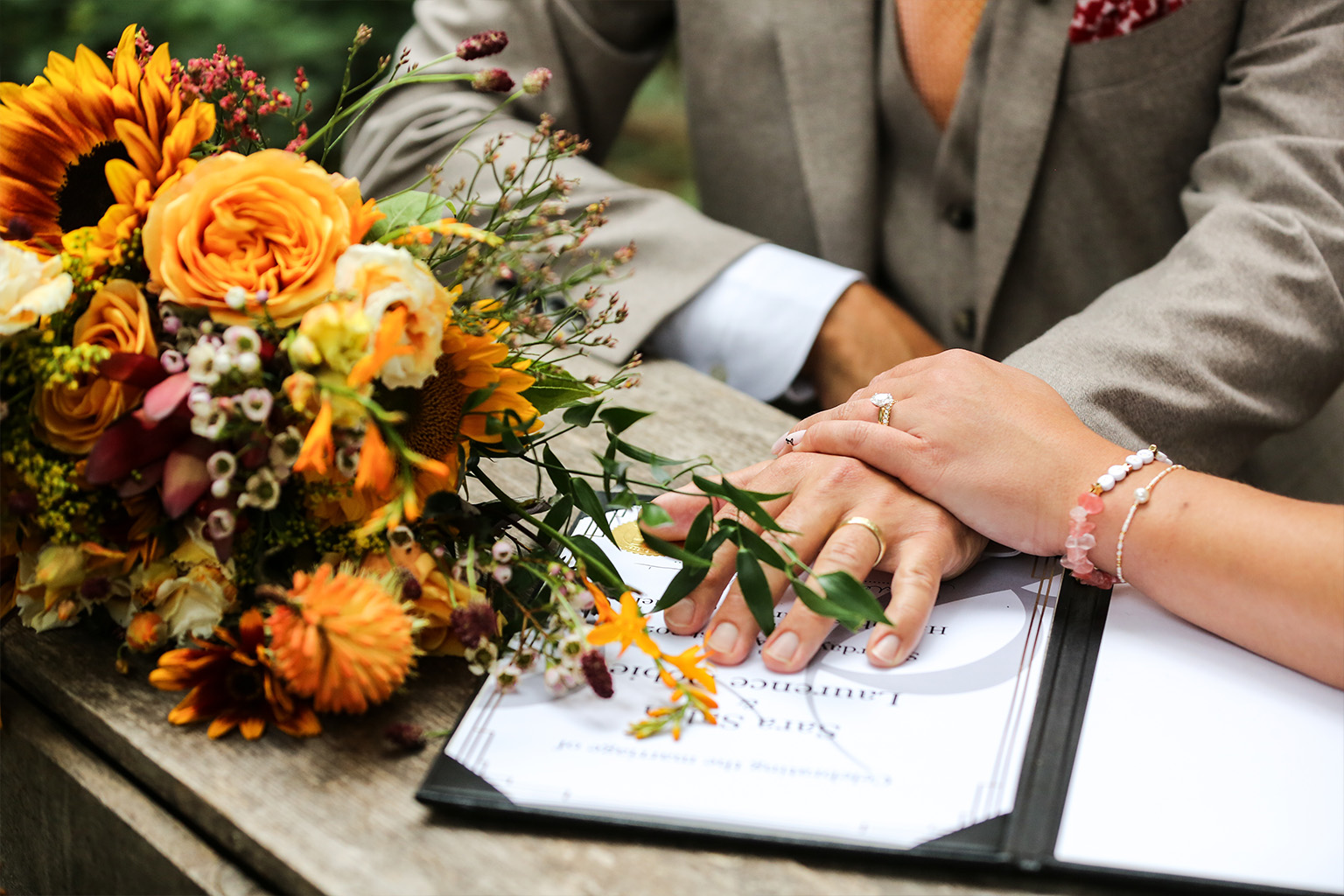 Bride and groom holding hands with wedding rings during a ceremony signing moment at a Dorset wedding