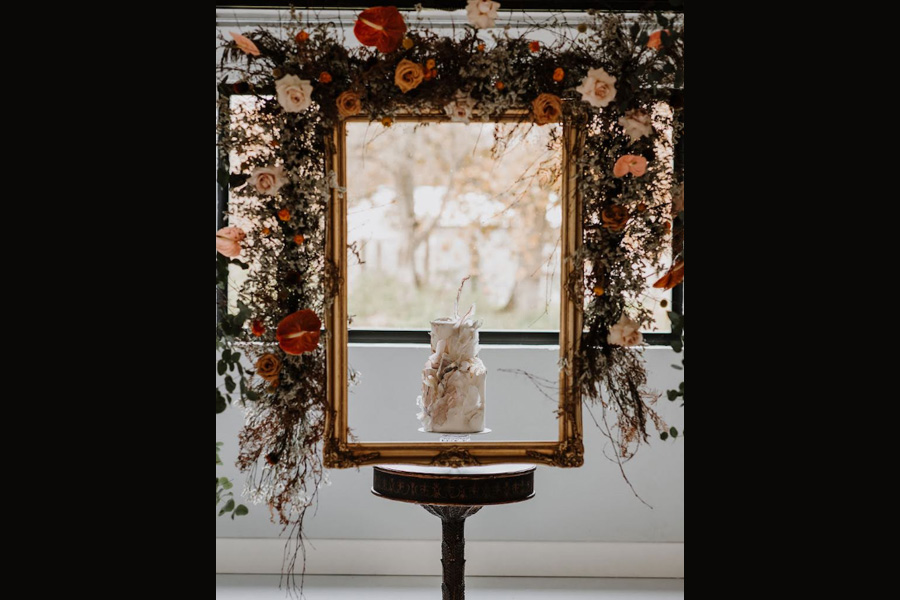 artistic wedding cake framed by floral installation in window display by Bonita Bakes