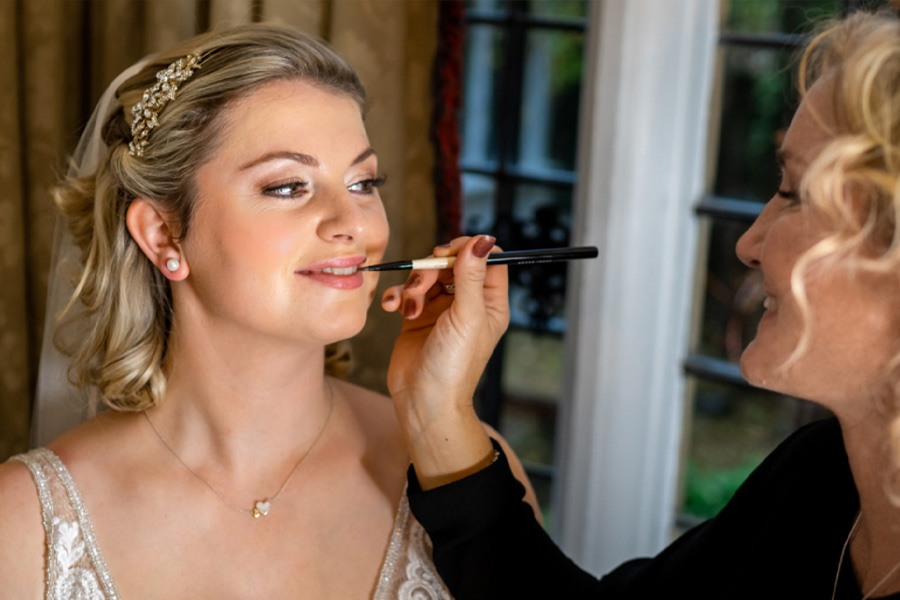 Bride having makeup applied during wedding morning preparations with soft natural light