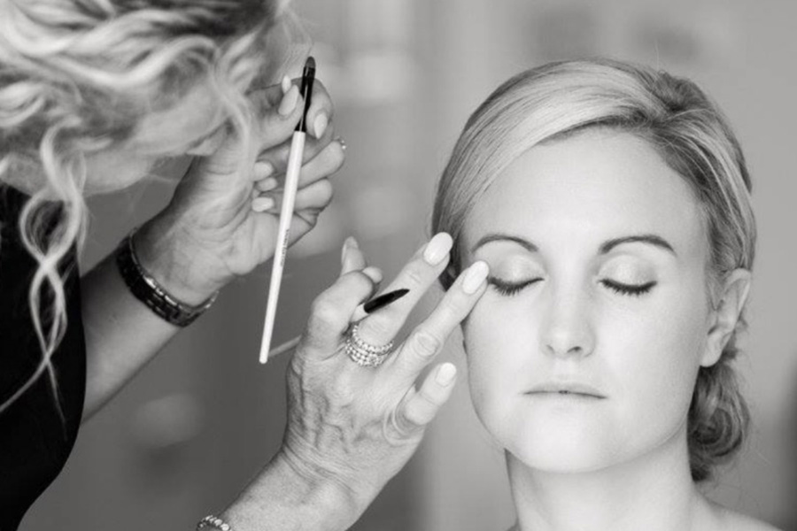 Black and white image of bridal makeup being applied during wedding morning preparations