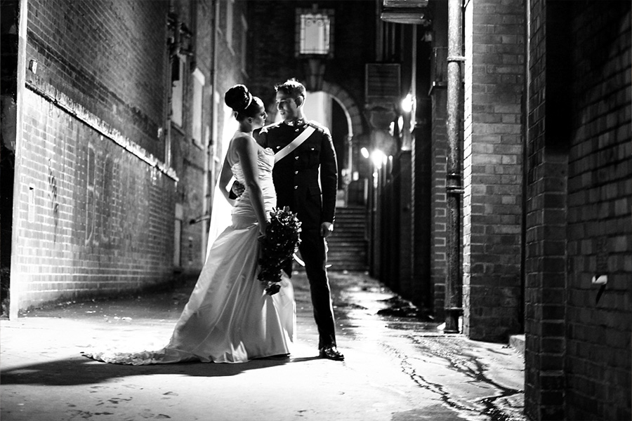 Bride and groom sharing a romantic moment at night in a city alley, capturing authentic wedding photography storytelling
