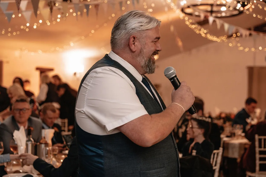 Chris Howat Magic performing as a wedding emcee speaking into microphone during Dorset wedding reception