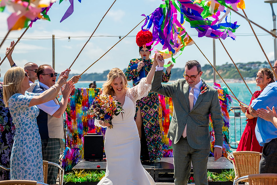 Drag queen wedding celebrant leading colourful inclusive beach wedding ceremony UK
