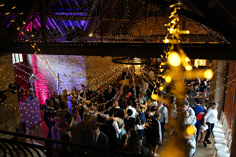 evening wedding reception inside a Hampshire barn wedding venue with fairy lights and guests