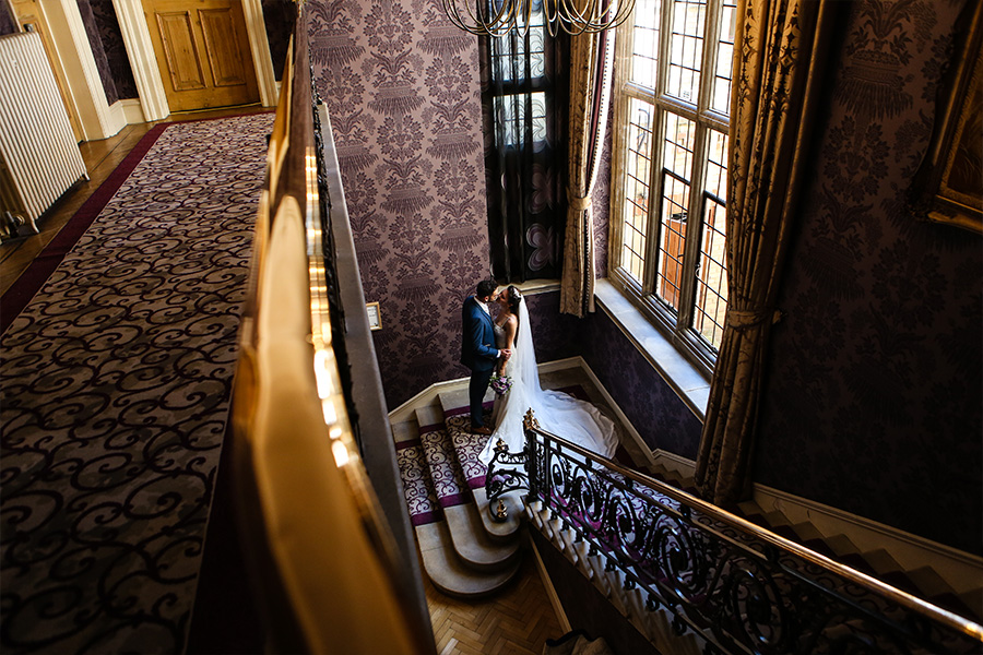 bride and groom on staircase inside a Hampshire country house wedding venue with elegant interior