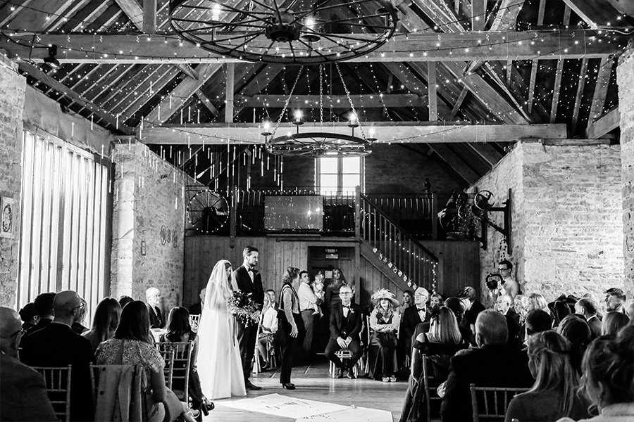 Indoor barn wedding ceremony at Kingston Country Courtyard Dorset with rustic beams and guests