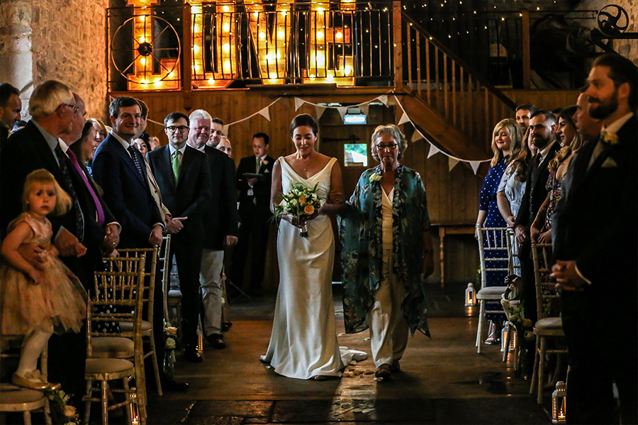 Bride walking down the aisle during indoor wedding ceremony at Kingston Country Courtyard Dorset