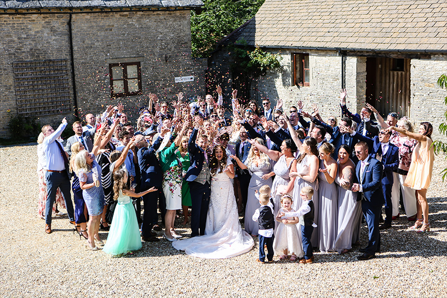 Wedding confetti group photo at Kingston Country Courtyard Dorset with guests celebrating