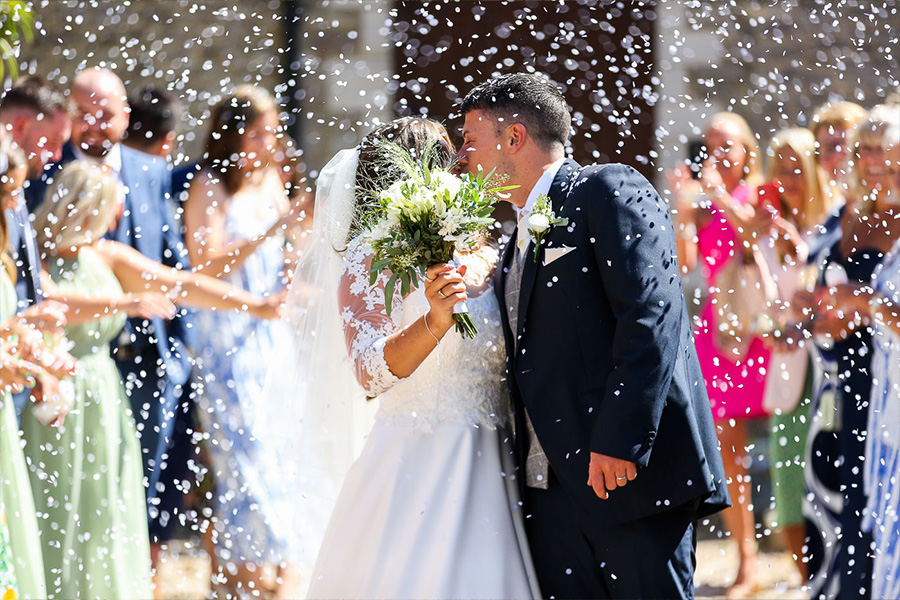 Bride and groom kissing during confetti moment at Kingston Country Courtyard Dorset