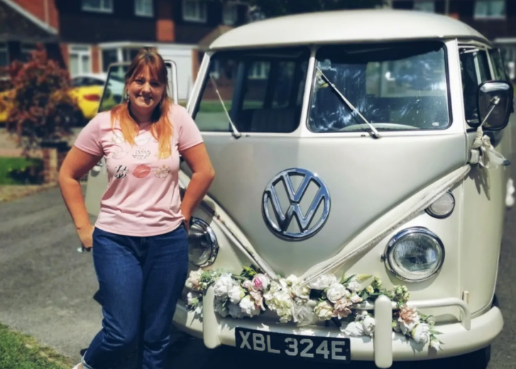 Lauren O MUA wedding hair and makeup artist standing beside vintage wedding camper van