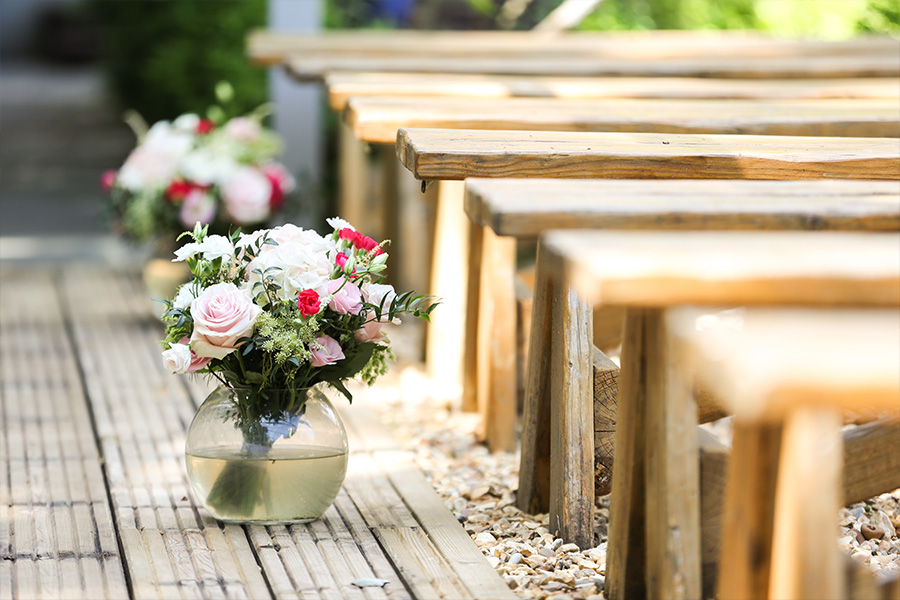 Wedding ceremony aisle flowers at The Old Vicarage wedding venue Dorset with wooden seating and garden setting