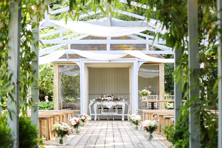Outdoor wedding ceremony setup at The Old Vicarage wedding venue Dorset with floral aisle and covered structure
