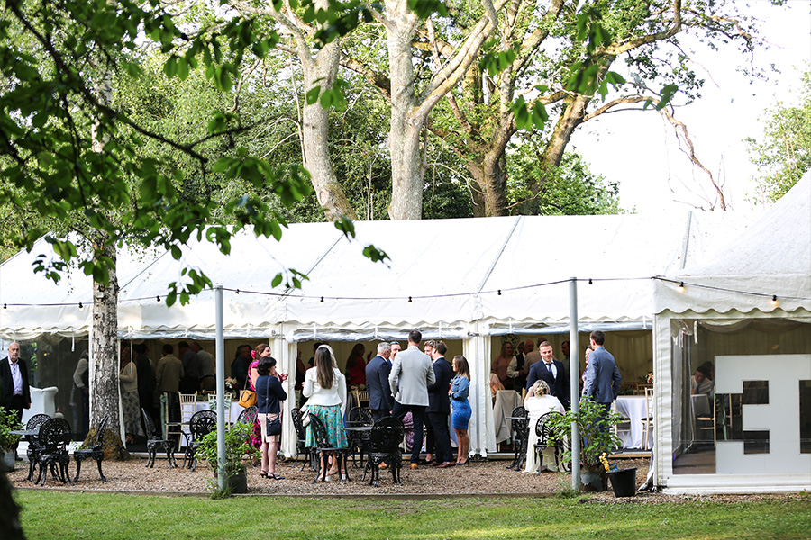 Guests gathered outside marquee at The Old Vicarage wedding venue Dorset garden reception setting