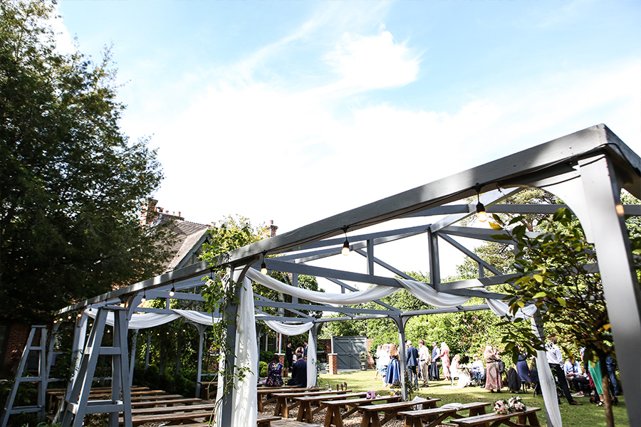 Outdoor ceremony structure at The Old Vicarage wedding venue Dorset with draped fabric and garden setting