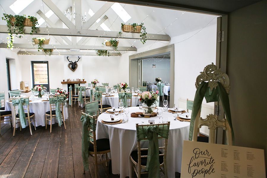 Wedding reception room at The Old Vicarage wedding venue Dorset with round tables greenery styling and wooden beams