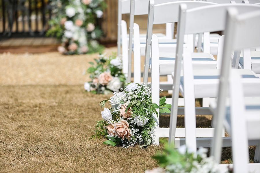 Wedding ceremony aisle flowers and white chairs at The Orangery Suite Dorset outdoor ceremony