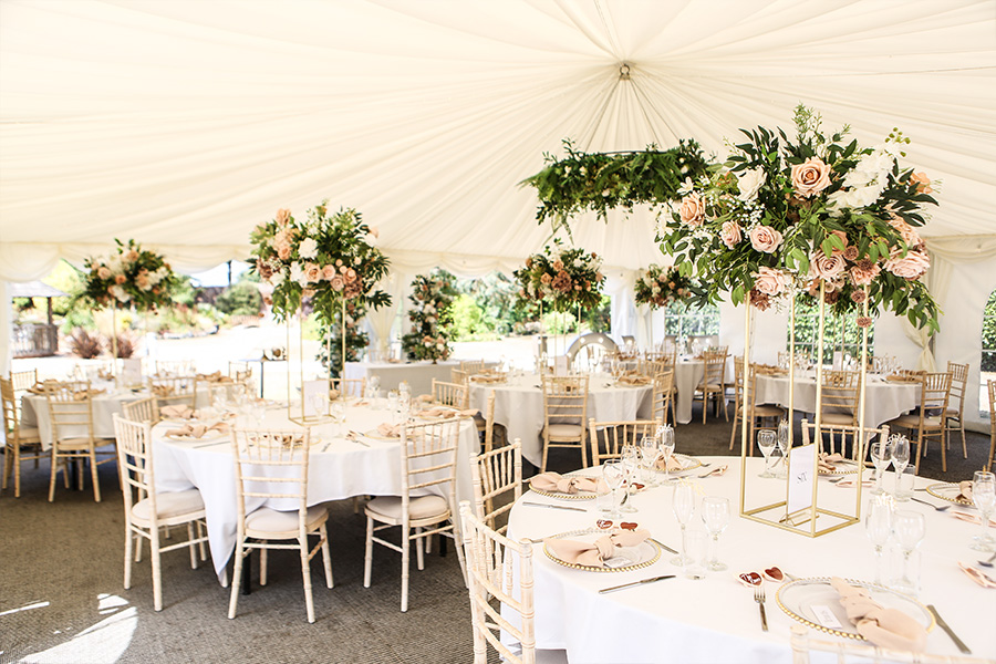 Wedding reception marquee interior at The Orangery Suite Dorset with floral centrepieces and round tables