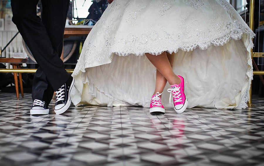 Bride and groom wearing trainers under wedding dress, representing planning your wedding and finding wedding suppliers in the UK
