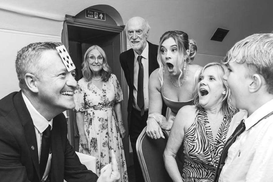 Southampton wedding magician Marcus Bailey performing a close up card trick with guests reacting in surprise at a Hampshire wedding