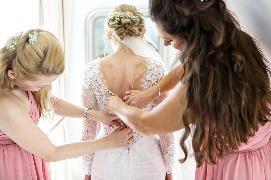 Bride getting ready with bridal hair styled and dress fastened Wiltshire