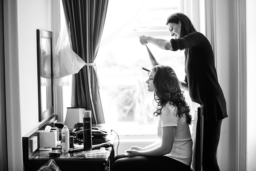 Bridal hair stylist creating curls during wedding morning preparation Wiltshire