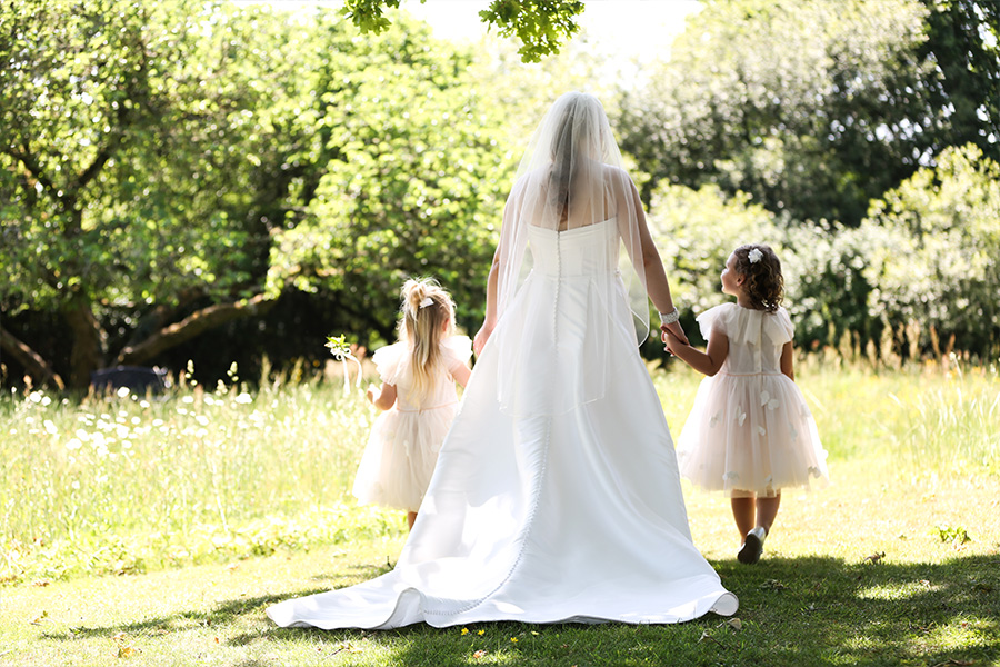 Bride walking with flower girls through the gardens at Bartley Lodge in the New Forest.