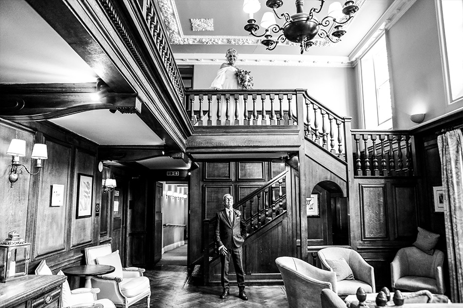 Bride and groom on the grand staircase inside Bartley Lodge wedding venue in Hampshire.